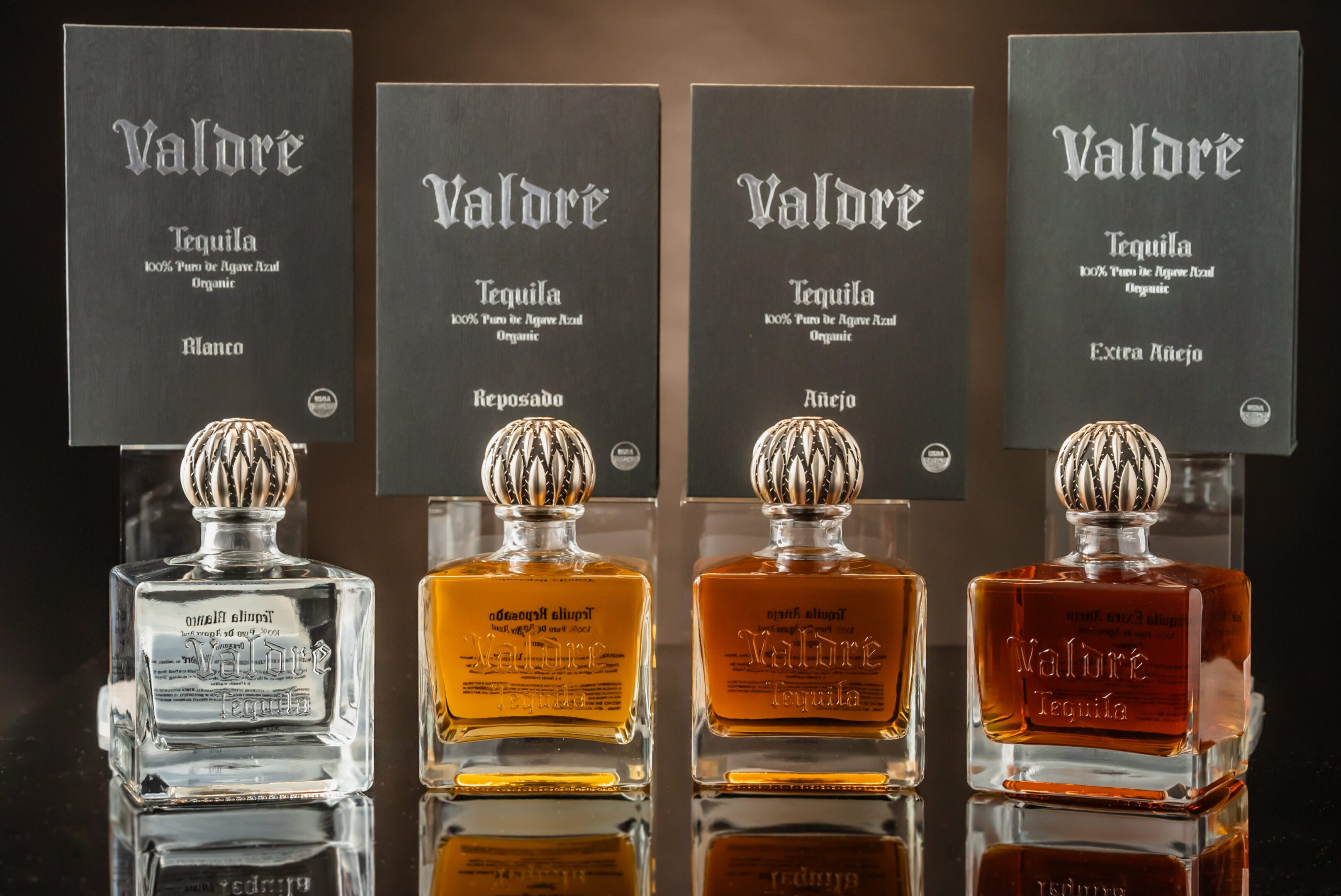 Four bottles of tequila are lined up on a table.