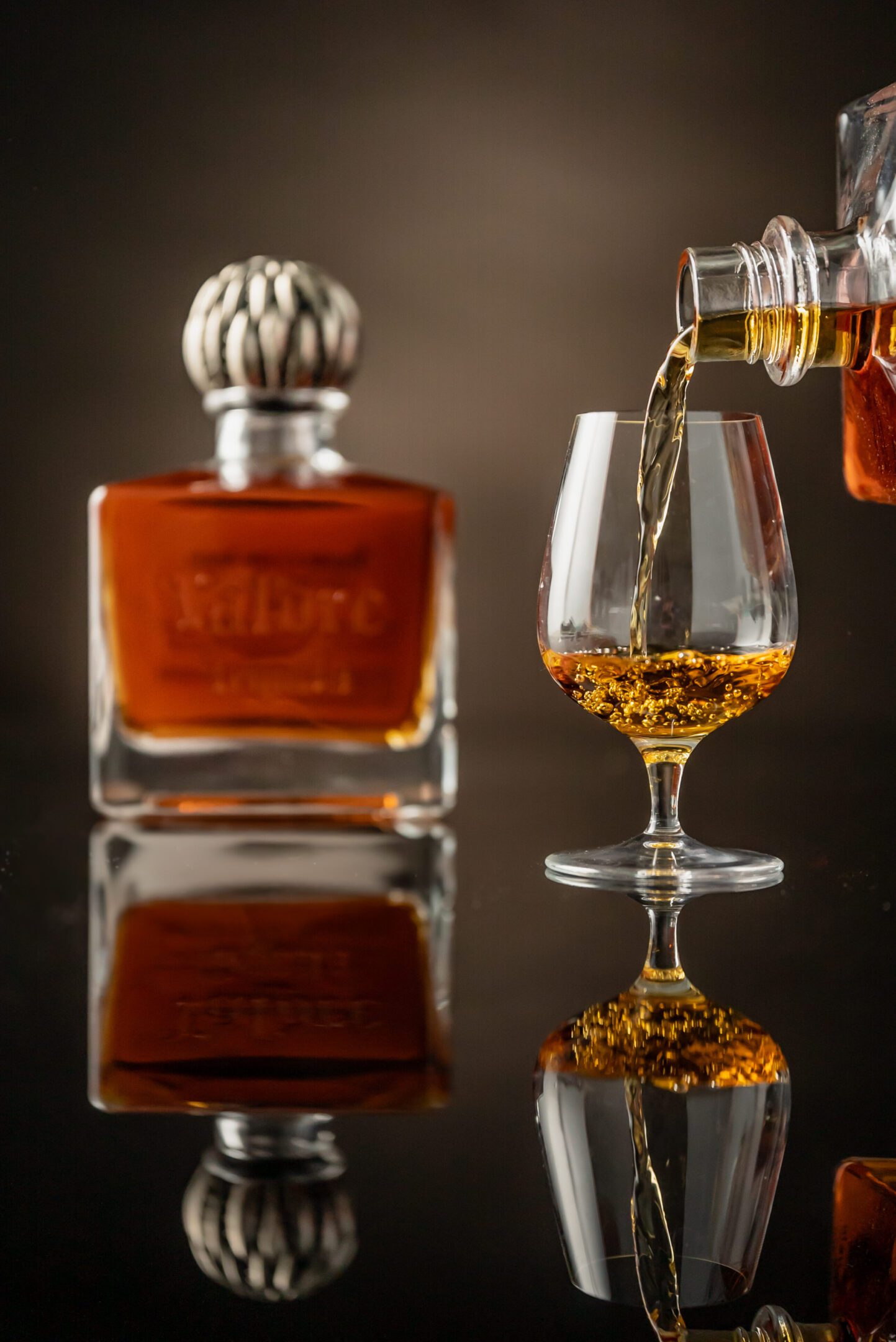 A glass of whiskey is being poured into it.